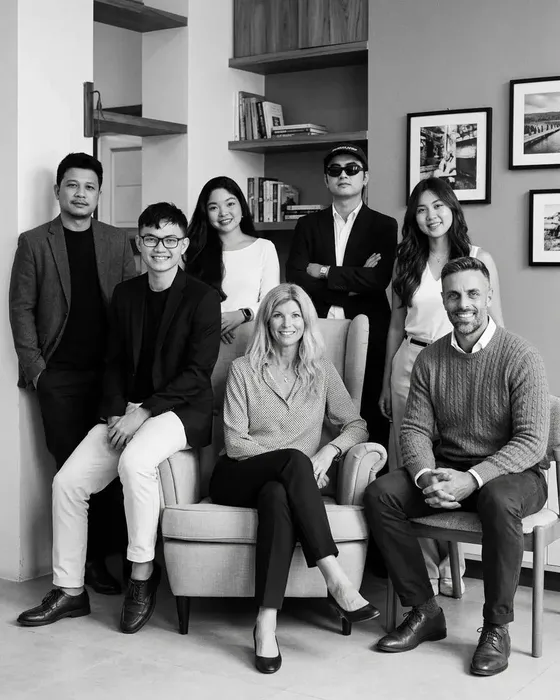 The Goss Group team, seven people gathered around an armchair in the office.